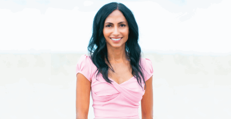 A woman in a pink dress smiling with a bright, blurred background.